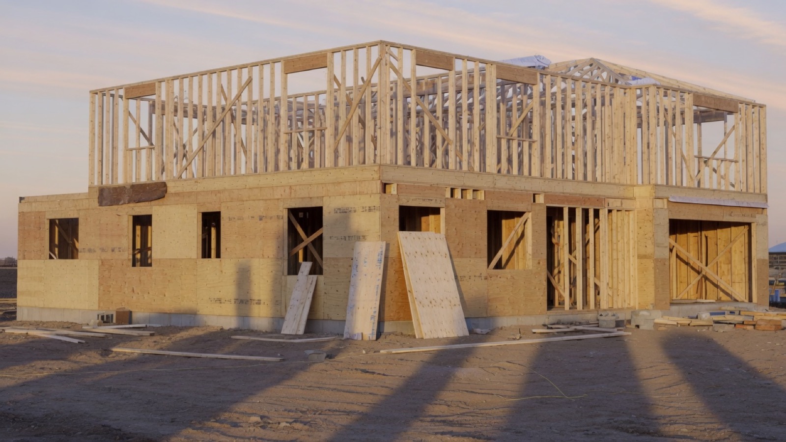 A newly framed two-story house at sunrise